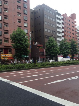 To the right of the 100 Yen shop, a taller building is built around a smaller one.